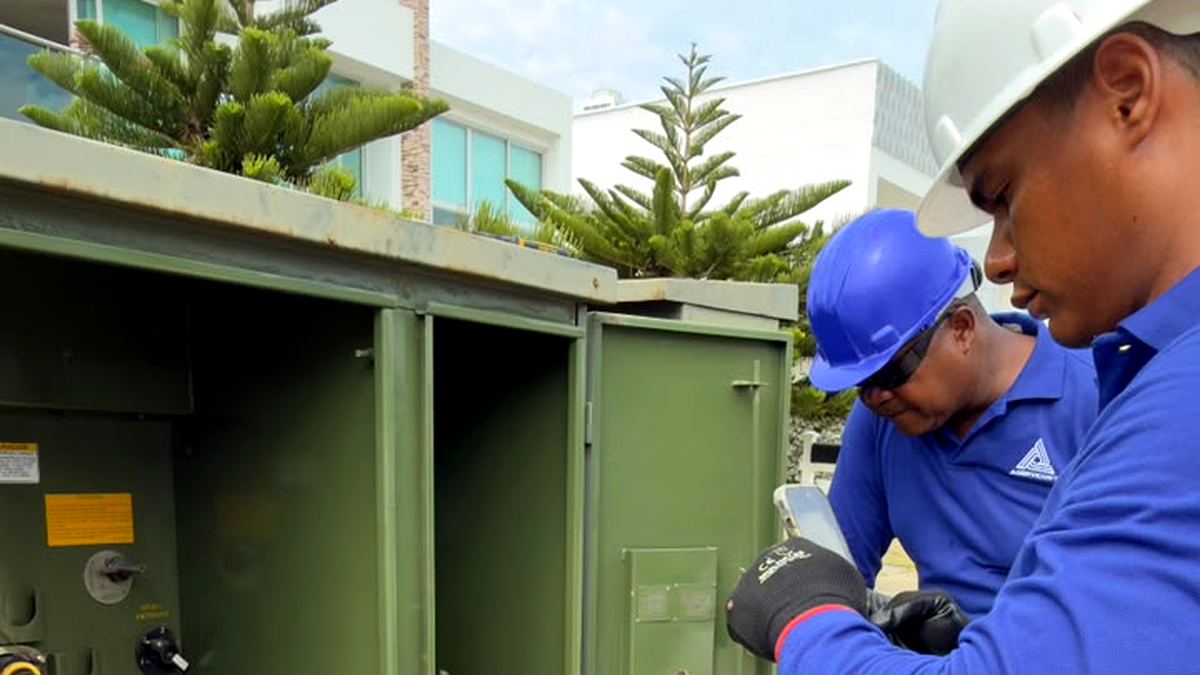 Dos técnicos trabajando en conjunto sobre transformador